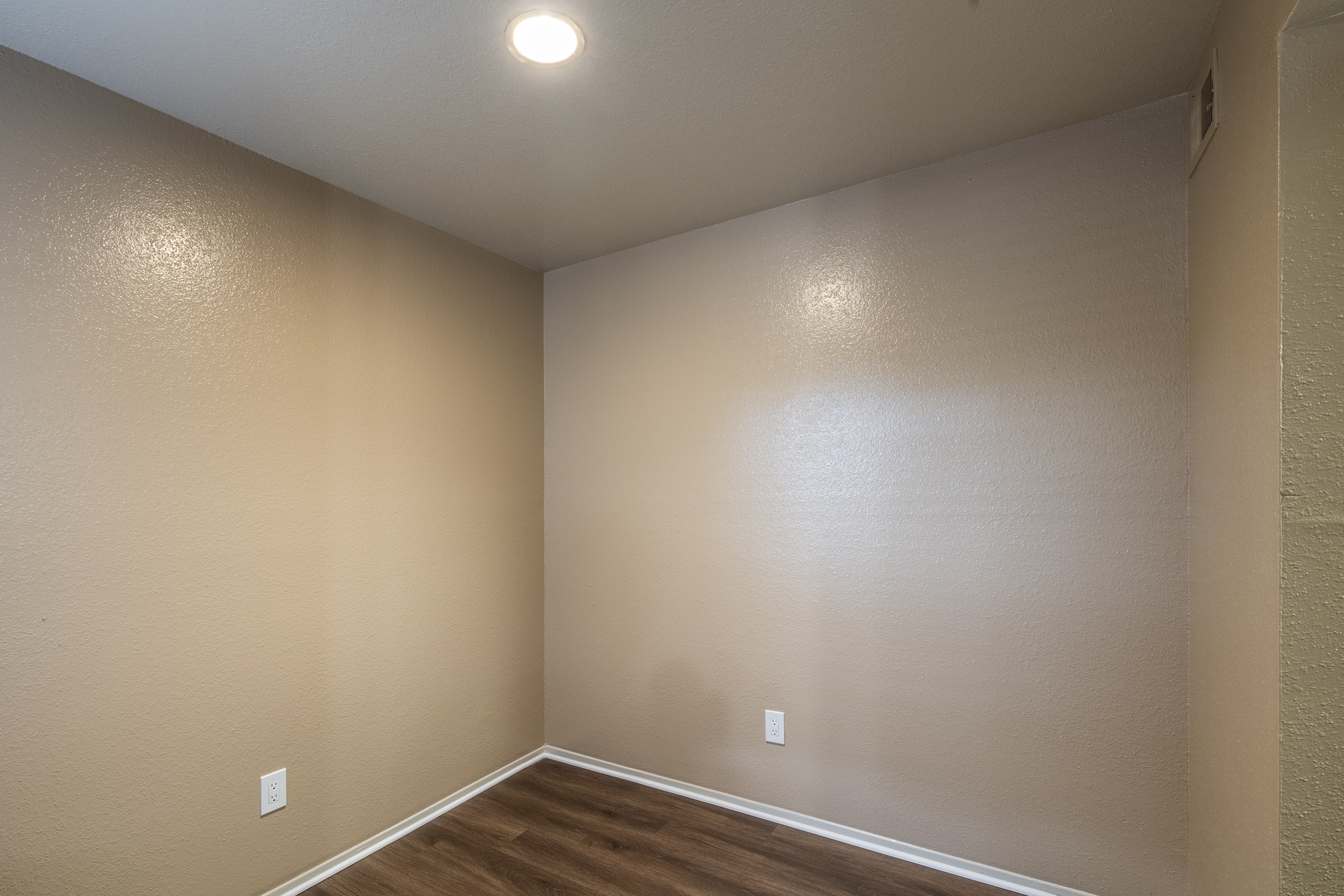 A room with a light on the ceiling and a light switch on the wall.
